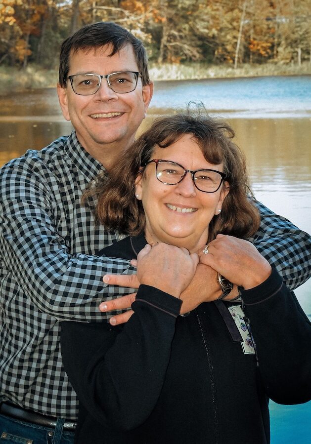 Pastor Larry Burg and Nancy Burg hugging in front of a Northern Minnesota lake.